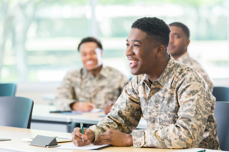 Students in army uniforms sit in a classroom.