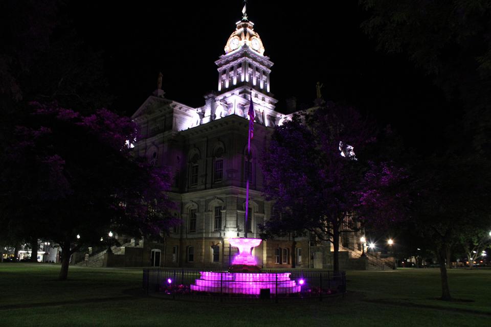 The Licking County Courthouse and a fountain list up at night.