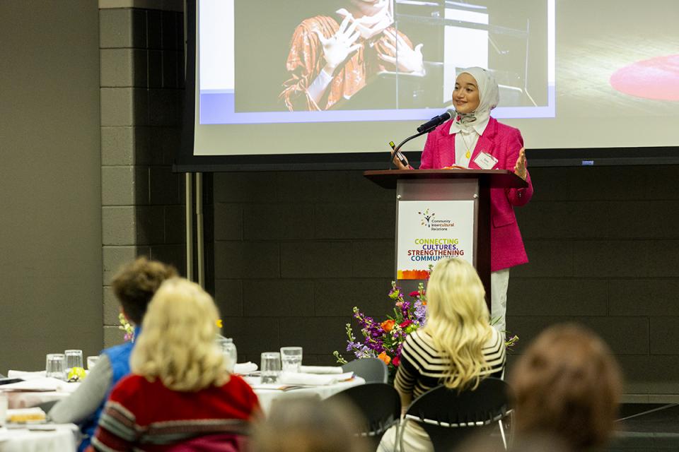 Opening speaker Sara Abou Rashed stands at a podium speaking to a room of conference attendees.