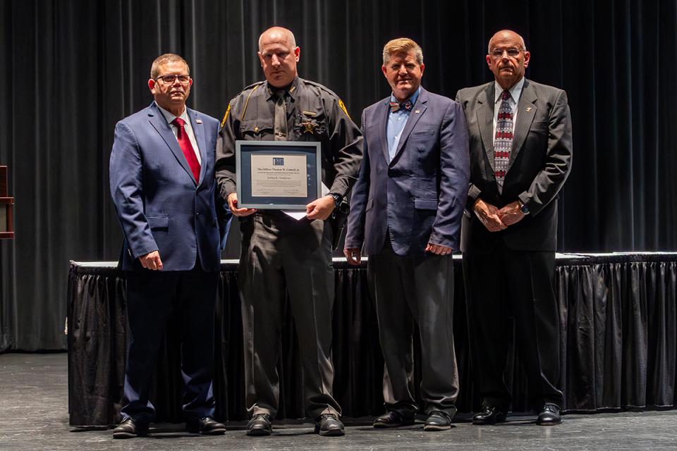 Commander James Rease; Joshua Snodgrass; President John Berry, PhD; and Commander Jeff Sowards Joshua Snodgrass stands on stage holding his award certificate with Commander James Rease; COTC President John Berry, PhD; and Commander Jeff Sowards.