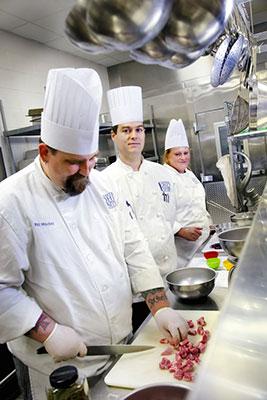 Three chefs preparing food in a kitchen