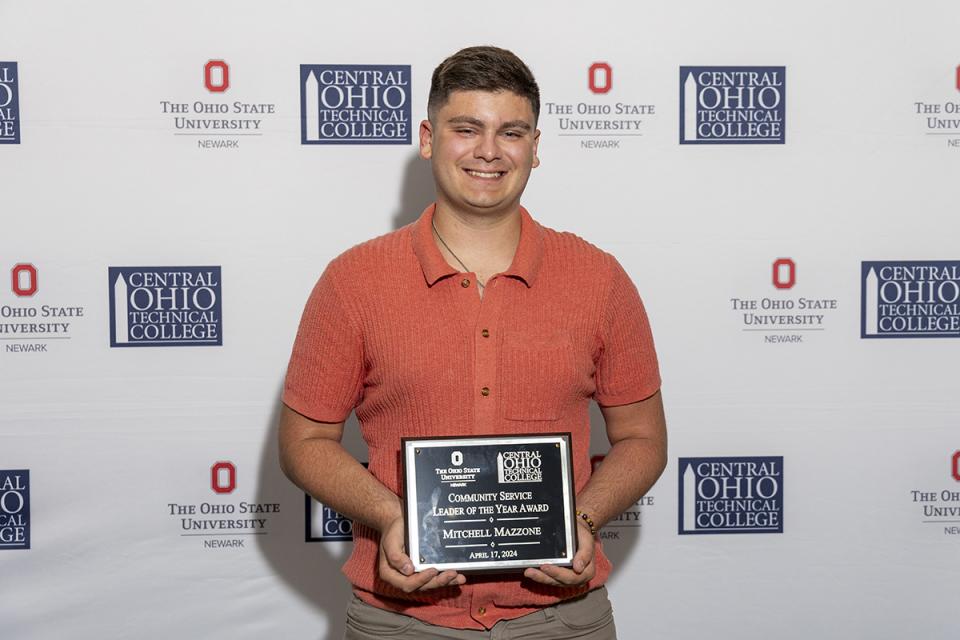 Mitchell Mazzone holds a plaque in recognition of receiving the Community Service Leader of the Year Award.