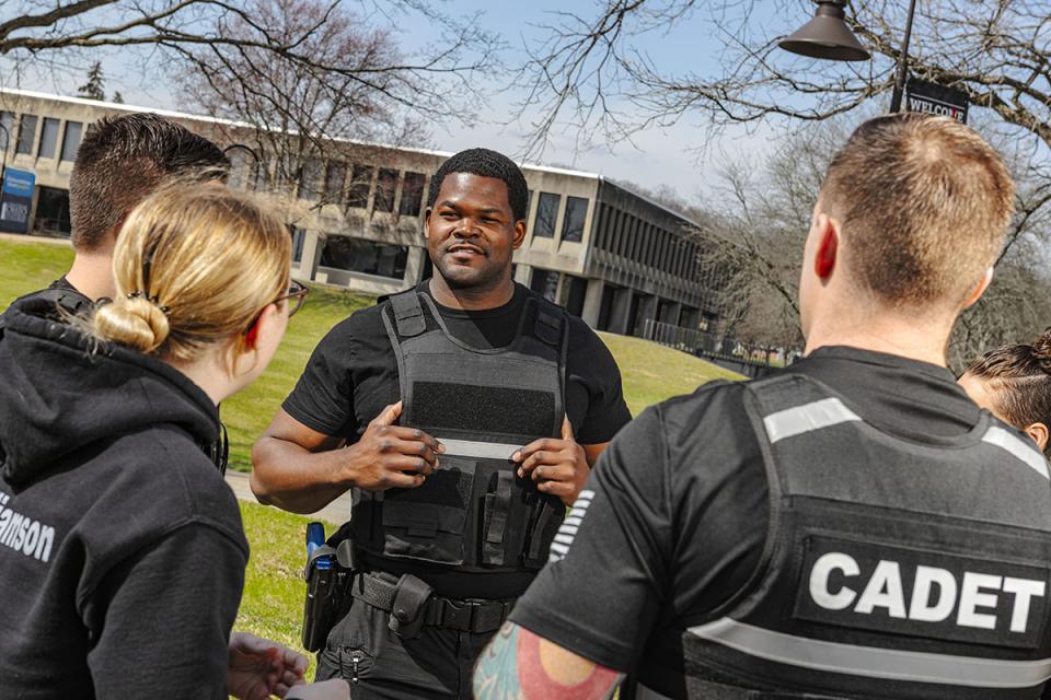 Students in cadet uniforms stand in a circle talking to each other.