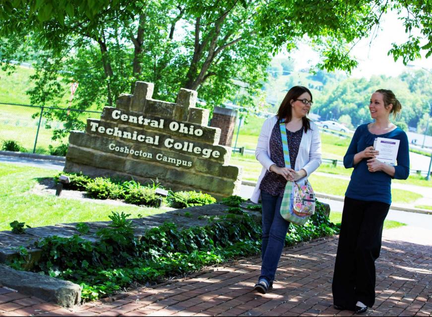 2 girls walking outside Coshocton campus building