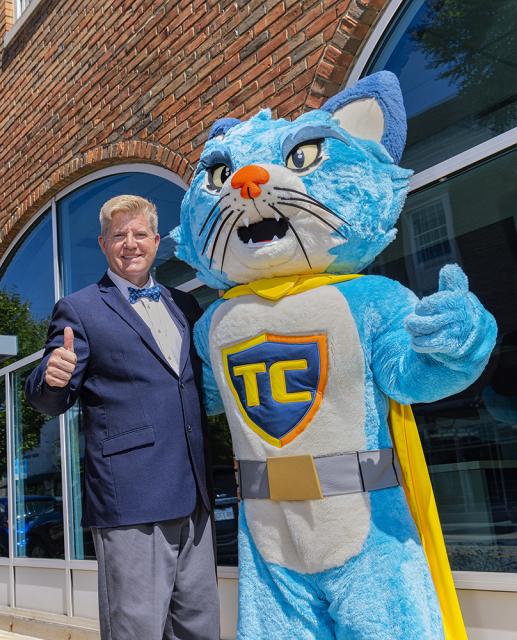 Dr. Berry and TC the cat mascot give a thumbs up outside the COTC Coshocton campus.