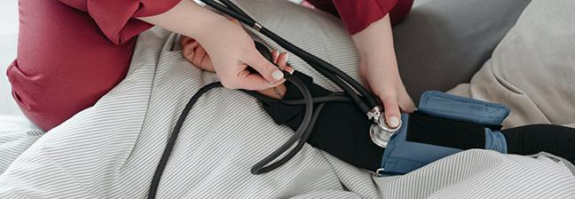 female technician taking blood pressure of patient