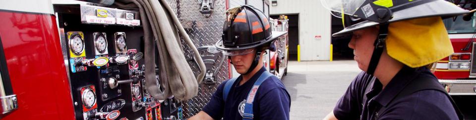 2 fire fighters working on fire truck controls