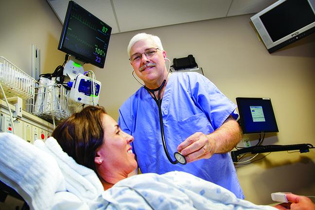 Male nursing student attending patient in bed