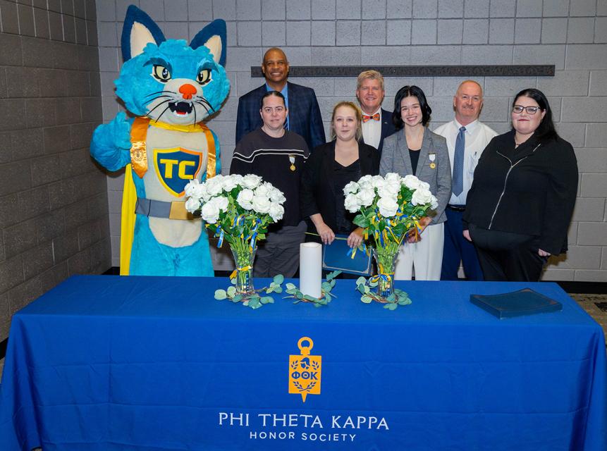 PTK inductees, COTC staff and TC the cat mascot attend an induction ceremony for new members.