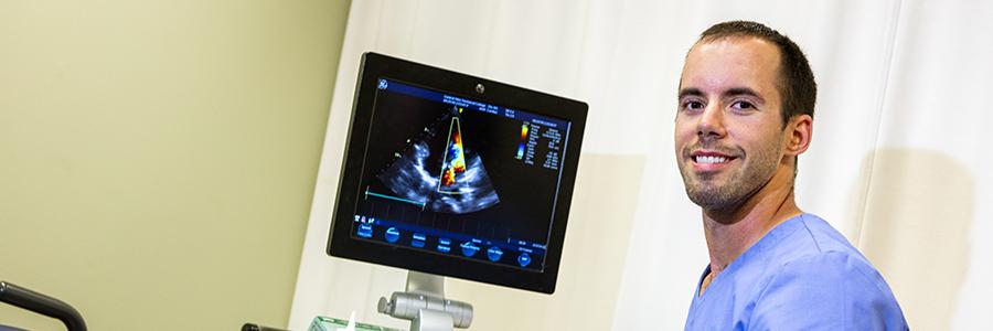 Sonography student next to ultrasound machine