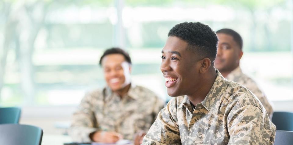 Students in army fatigues sit in a classroom.